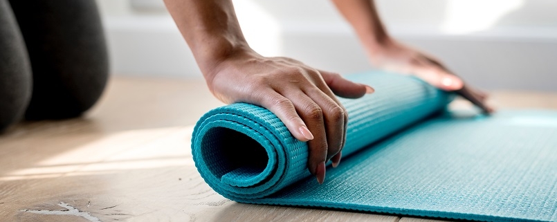 hands rolling yoga mat in studio