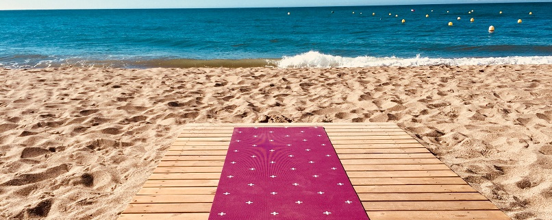 yoga mat on wooden decking overlooking sandy beach and sea