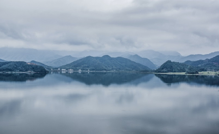 Misty lake scene with hills and trees in background