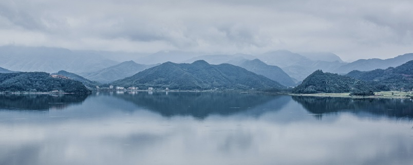 Misty lake scene with hills and trees in background